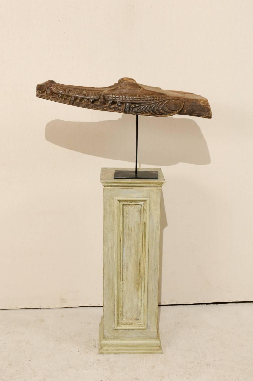 A carved wood crocodile head boat prow from Papua New Guinea. This mid-20th century Papua New Guinean boat prow has been carved out of wood and features the head of a crocodile. This boat prow is displayed on a custom black iron stand. The carvings