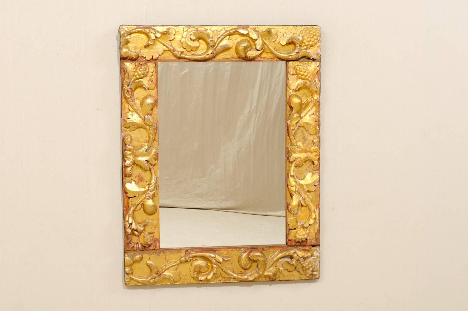 An Italian giltwood carved mirror made of 19th century fragments. This gilded rectangular Italian mirror is made of richly carved leafy scrolls decorating the frame. The surround is gesso over gilded wood, gold with spots of reddish ochre, nice age