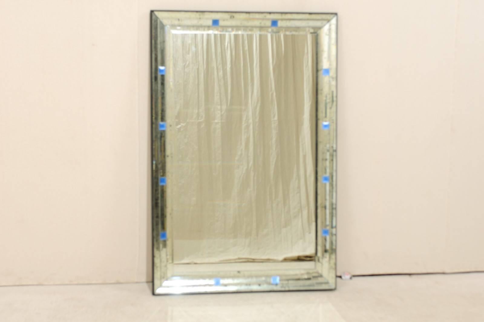 A pair of large-sized rectangular mirrors with small painted blue églomisé square glass accents and antiquing throughout its border. These mirrors also have a nice thin black frame around their edges. With the simplicity of its lines and discreet