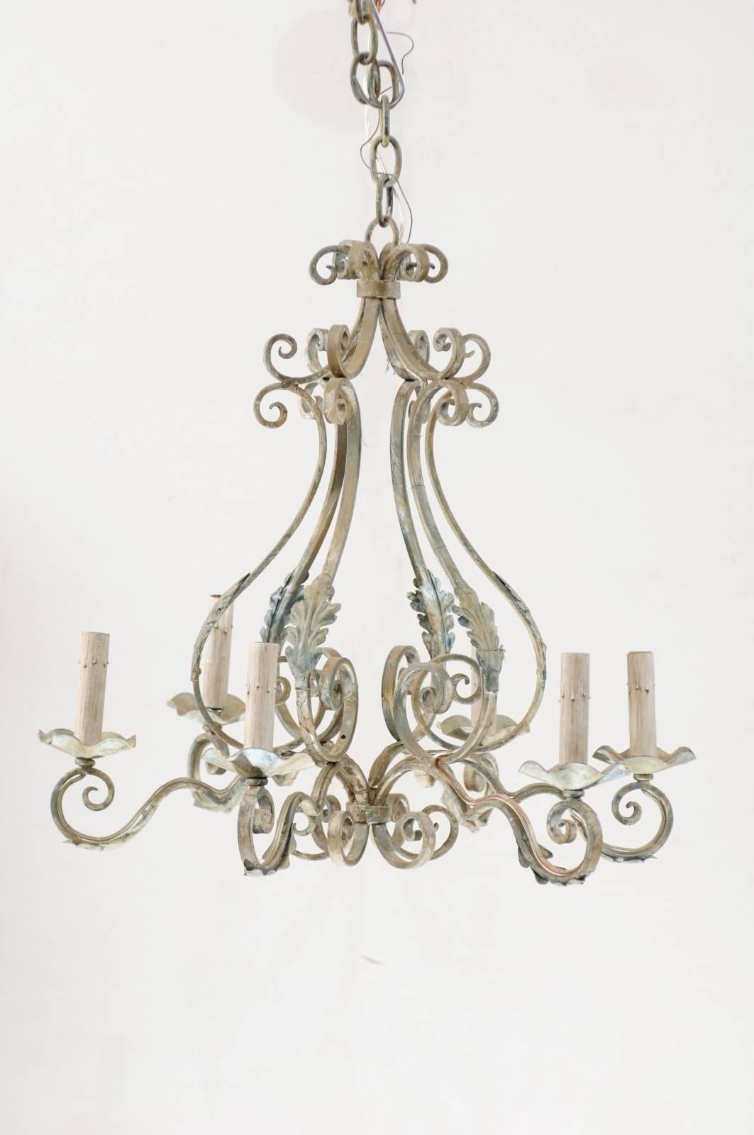 A French six-light pear shaped painted iron chandelier. This French chandelier from the mid-20th century features flowing scroll and acanthus leaf motifs throughout. Six scrolled arms lead out to candle sleeves that house light sockets. This iron
