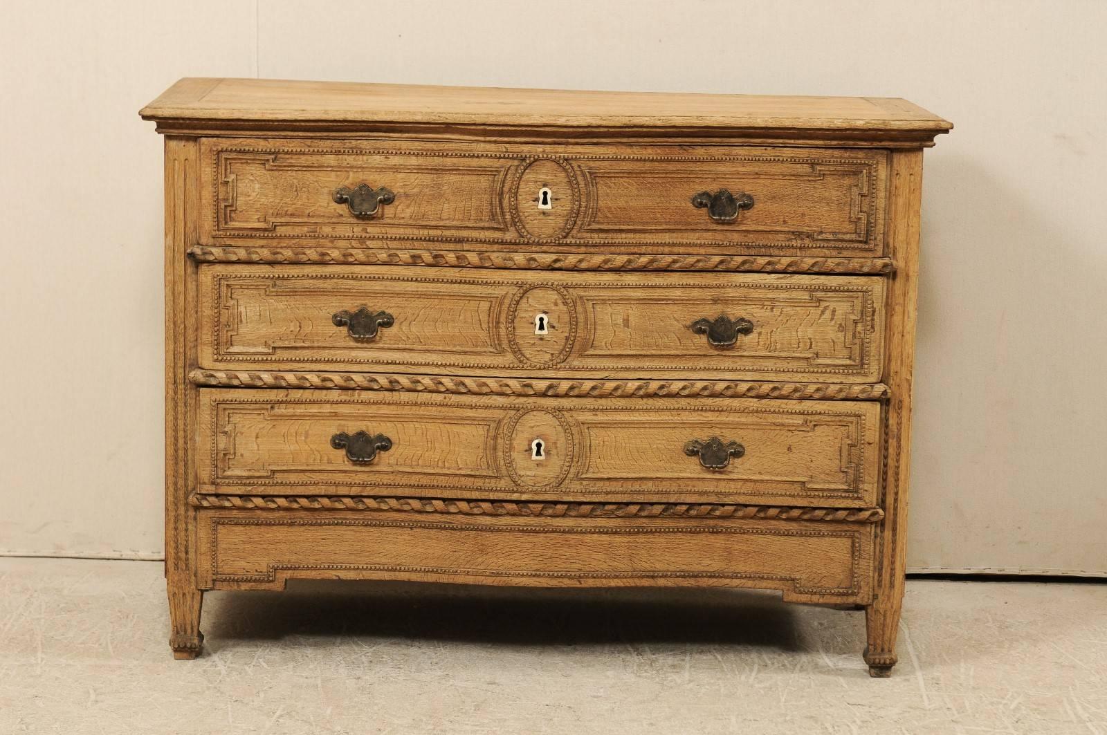 A late 18th-early 19th century French carved wood three-drawer chest. This French three-drawer chest features a soft serpentine style body of natural oakwood. Each of the three drawers are nicely carved in beaded and roped designs, flanked at either