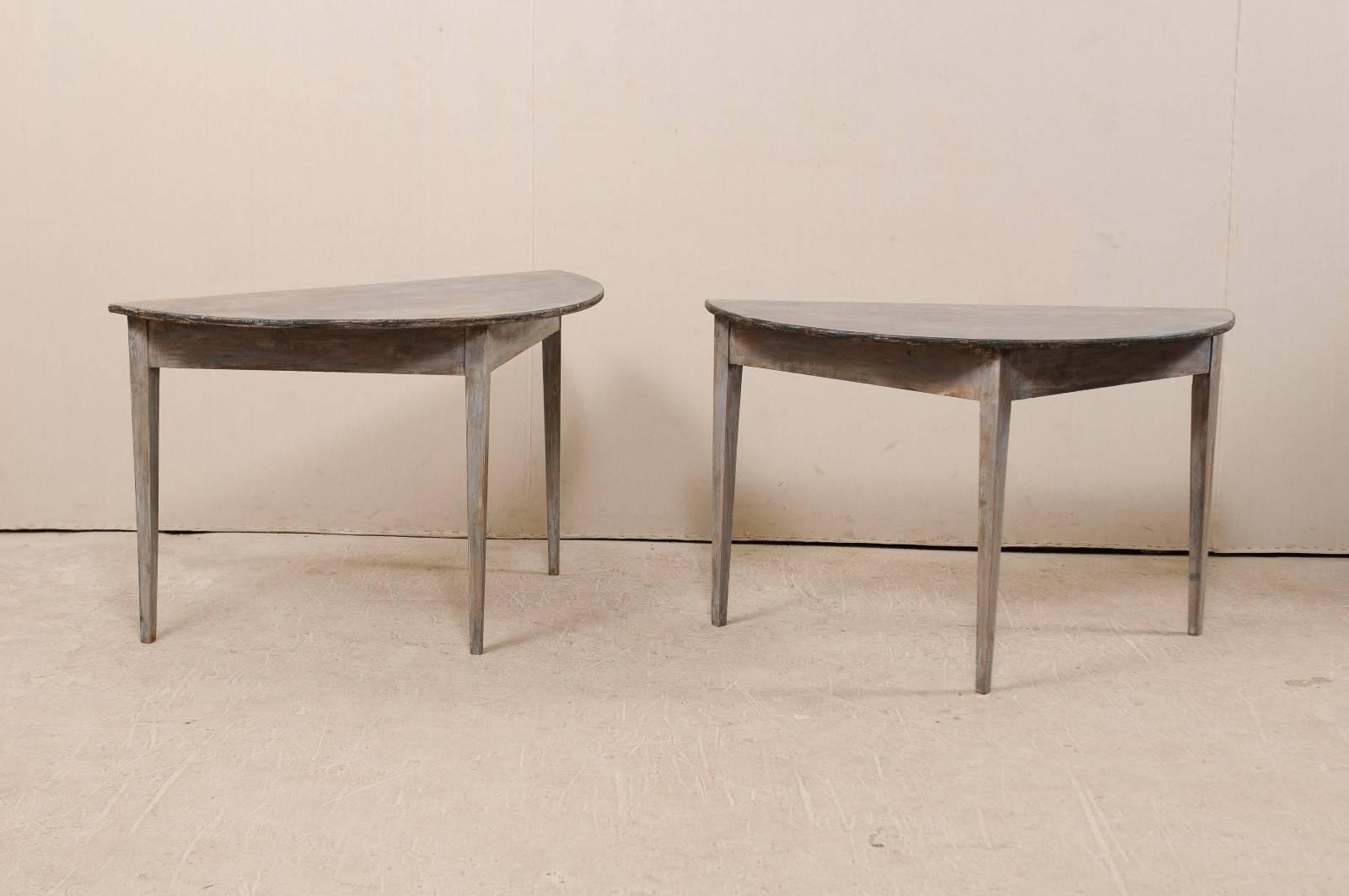 A pair of 19th century Swedish painted wood demilune tables. This pair of Swedish demilune table features a semi-circular top over a triangular shaped apron. These demilune tables are each raised upon three squared and gently tapered legs. The