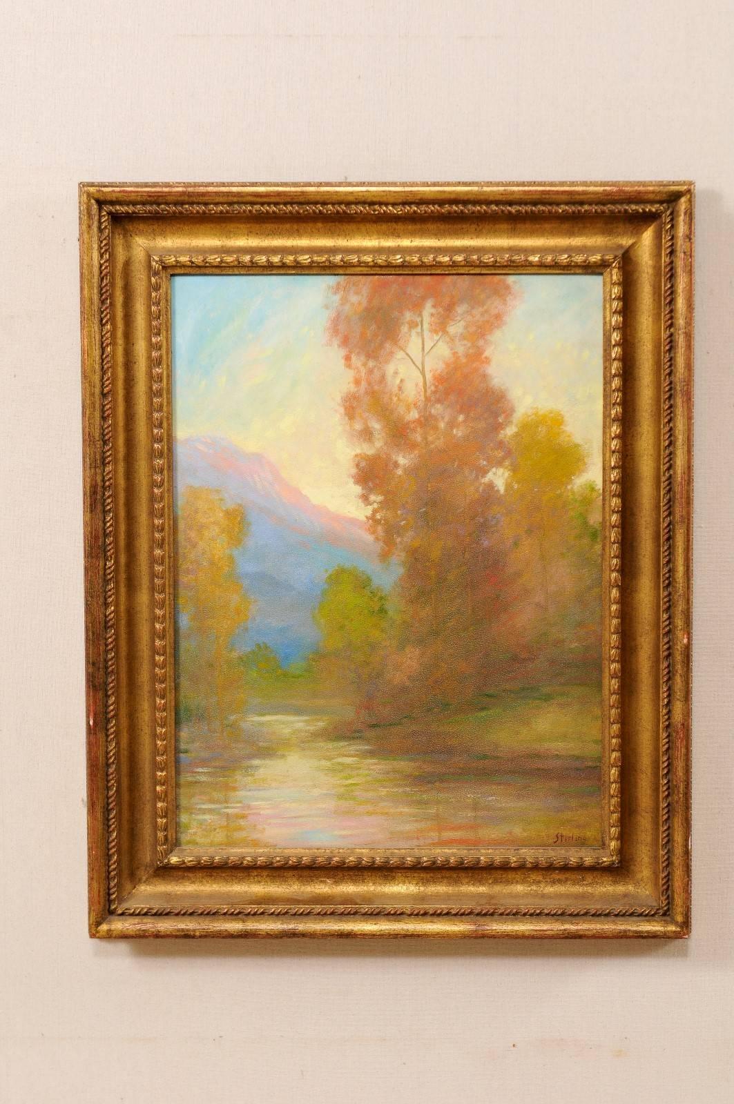 A David Sterling, American artist (1887-1971) landscape oil painting in frame. This is a romantic depiction of a water source surrounded by autumn trees and mountain in the distance. This painting is within a gold wood carved frame. Signed