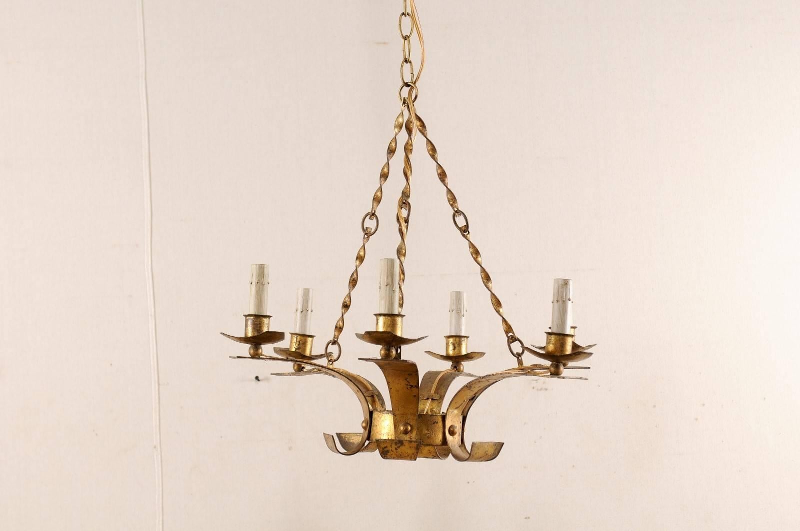 A French mid-20th century six-light chandelier. This French chandelier has a modern design featuring a small circular centre with six arms rising up and out from the centre, each supporting their metal bobèches and painted candle sleeves at the top