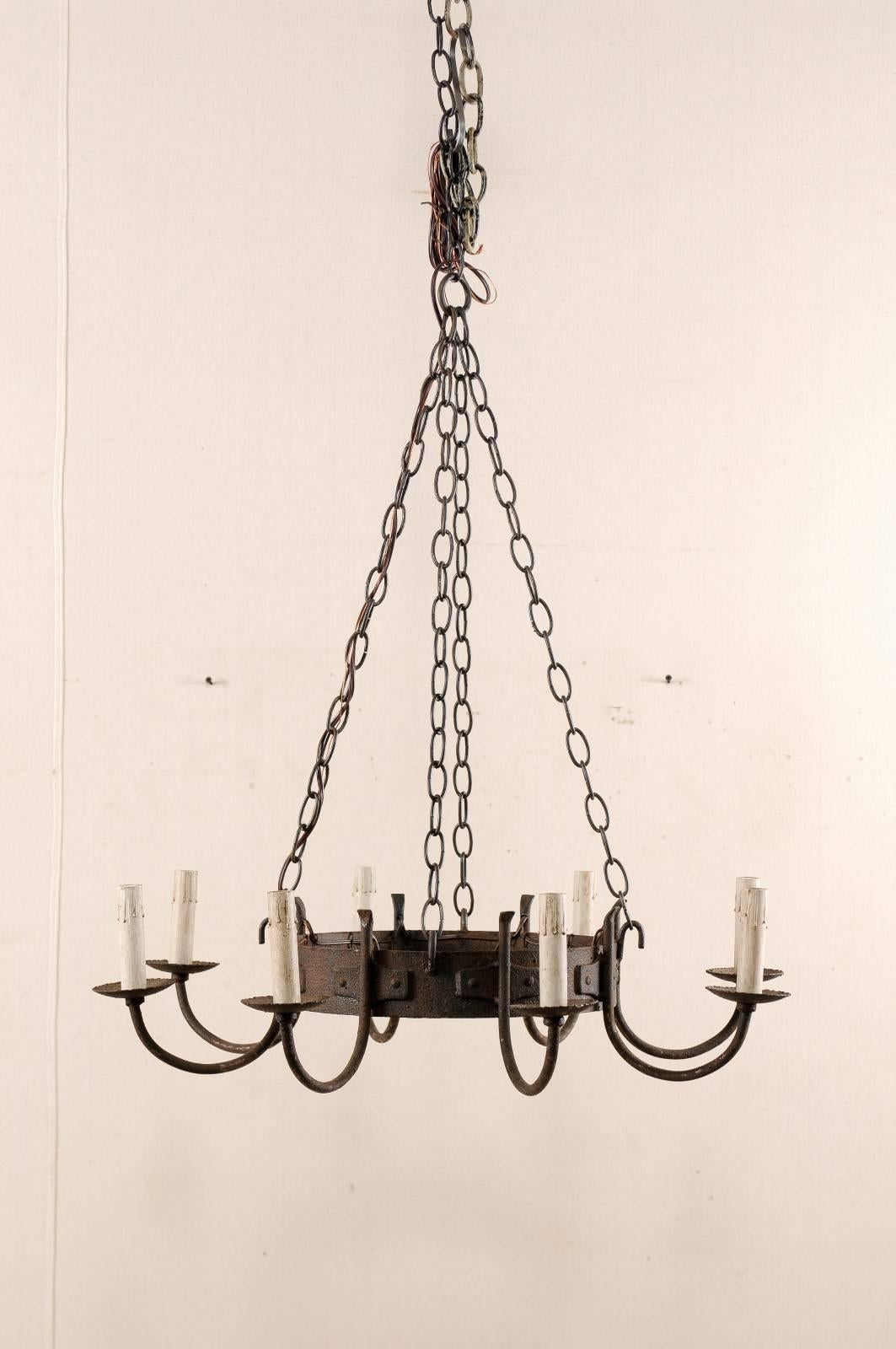 A French mid-20th century eight-light circular chandelier. This French chandelier, from the mid-20th century, features a circular shaped centre body with eight c-swooping arms flowing out from the exterior of the ring. Each of the swooping arms