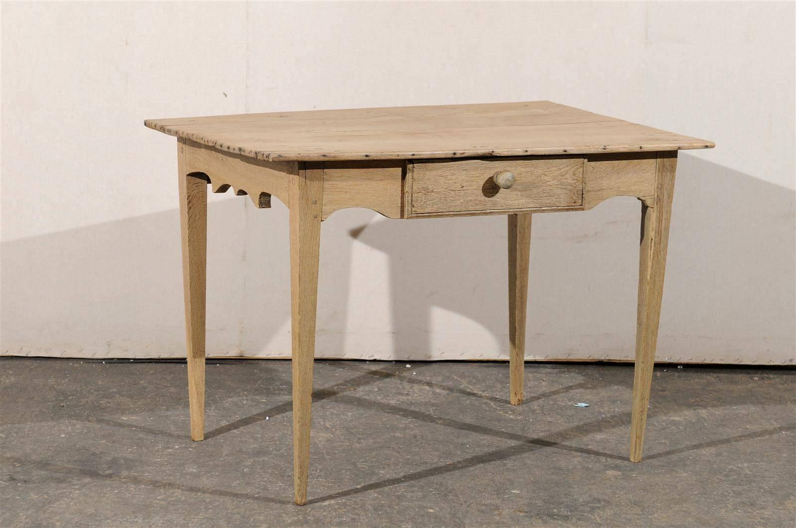 A French early 19th century side table with single drawer. This French wood side table features an interestingly carved skirt and sits upon four tapered legs. This table would work well beside a chair or couch.