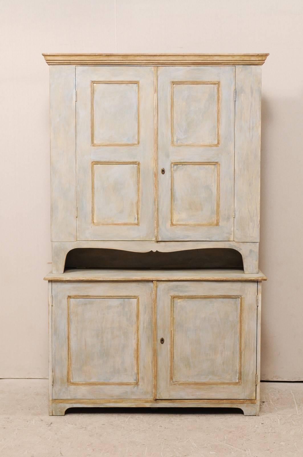 A Swedish mid-19th century painted wood cabinet. This Swedish cupboard features two recessed paneled doors, over the bottom case with two additional recessed paneled doors. There is an open and gently swagged section which separates the top from the