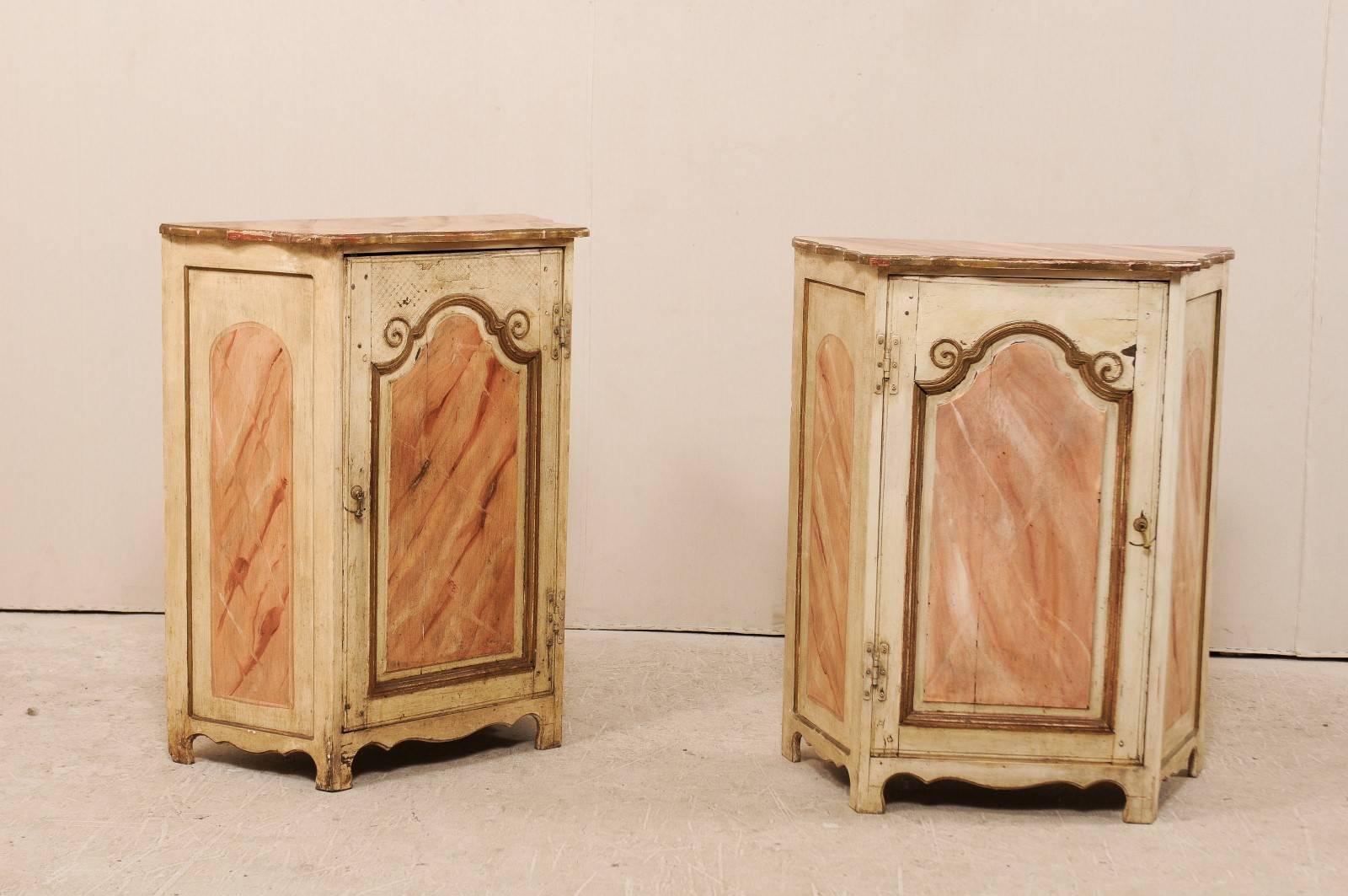 A pair of Italian early 20th century small painted wood commodini. These Italian chests each feature a single door with recess panel which has an arched top, flanked by two scrolls at either side. The top door panels and sides have all been painted