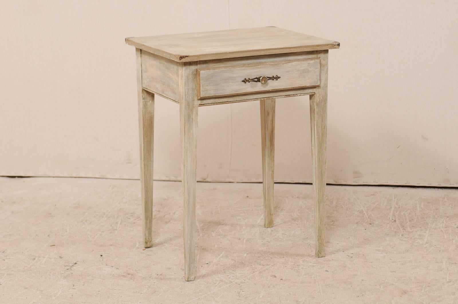 An American mid-20th century single drawer accent table. This American wood side table features a single drawer, rectangular top and squared legs. It is adorned with brass accents at each corner top, and brass knob with backplate on the drawer. This