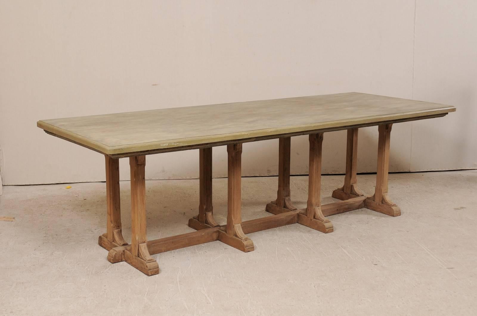 A vintage American trestle dining table. This American made eight-legged dining table features a trestle base which been constructed of old Indian teak wood. The long, rectangular shaped wood top has a light wash of grey, green, cream and blue. The
