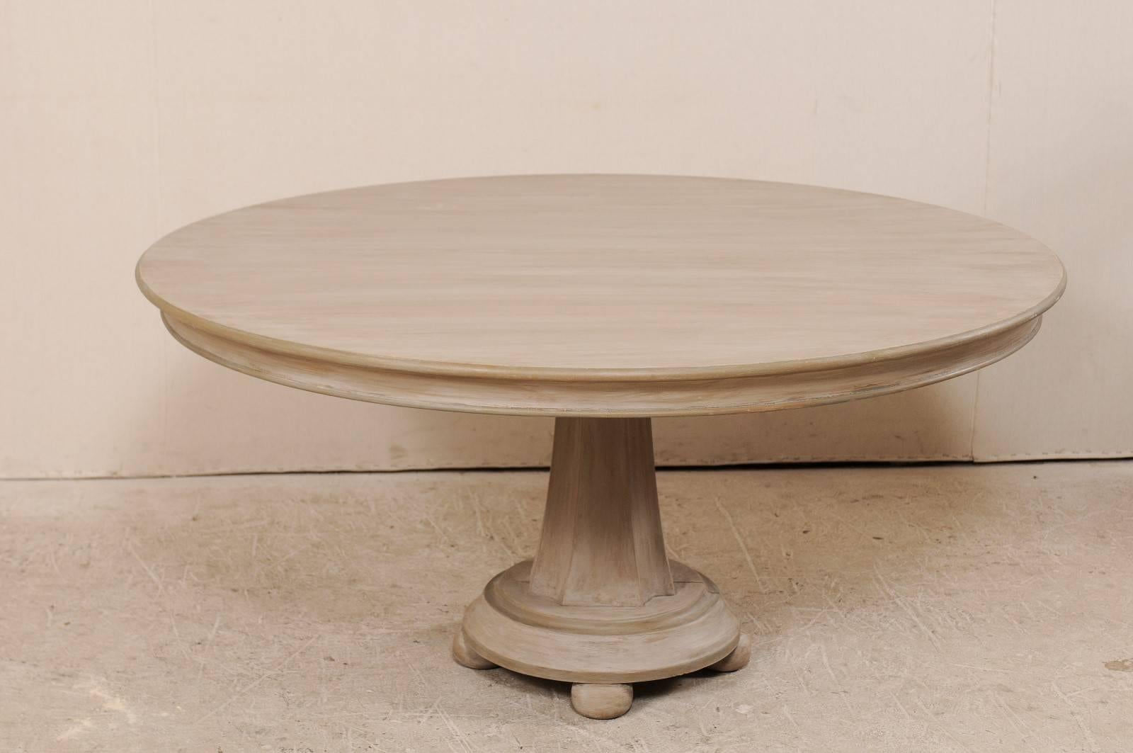 A vintage American pedestal table with mirror top. This American wood table features a central carved pedestal base which is raised up on round bun feet. A custom aged mirror rests on the top, creating interest and elegance to this table. The wood