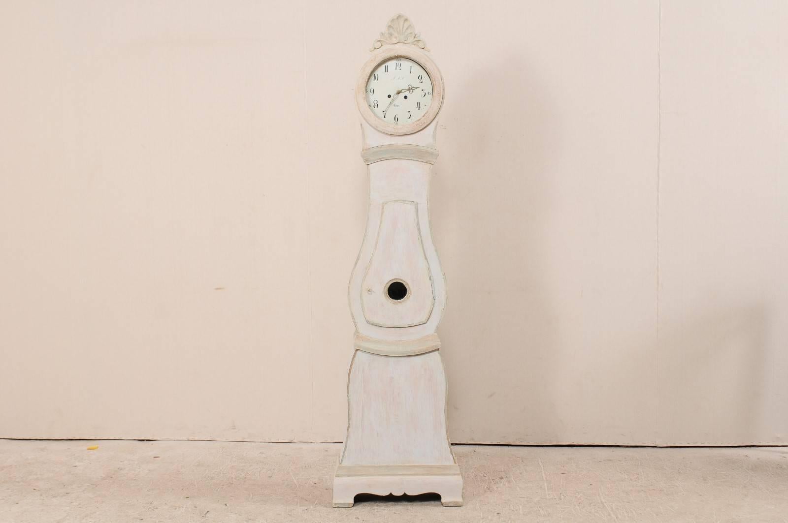 A Swedish, 19th century painted wood clock with original metal face. This is a lovely example of a Swedish Mora clock. This clock features a sweetly carved and raised crest, circle face and teardrop shaped door. The base displays a subtle curviness,