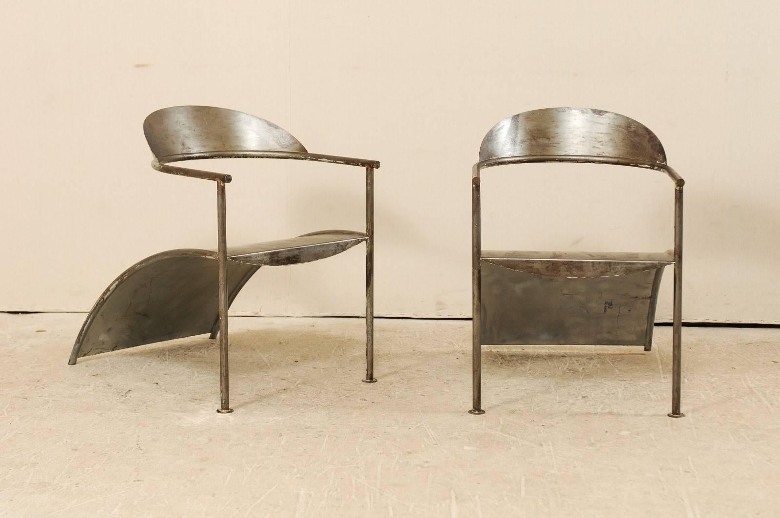 A pair of French metal chairs from designer Philippe Starck. These Philippe Starck metal lounge chairs, circa 1980, are striking and intellectual. Designed in clean lines about the arms and legs, paired nicely with a curved backrest and seat. The
