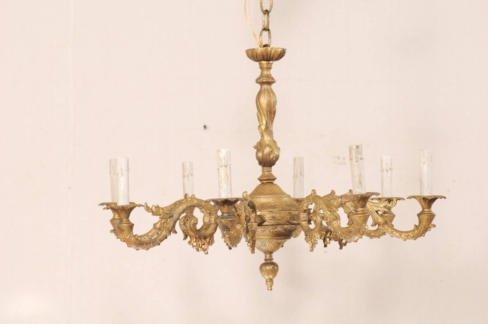 A vintage French eight-light painted gold metal chandelier. This French chandelier features eight S-scrolling shape arms reaching out from the central column to create a circular shape and terminate into the bobèches and painted candle sleeves. The