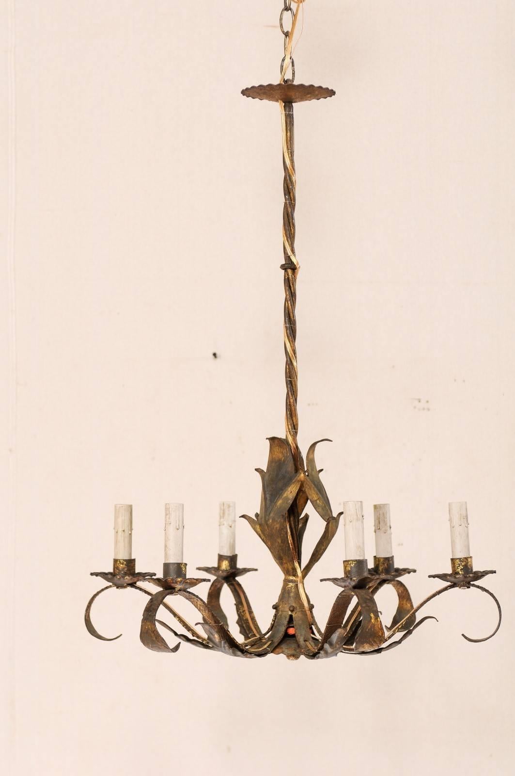 A French Mid-Century Modern six-light chandelier. This French chandelier has a modern design featuring a central column of metal leaves, gathered at the center, and flow outward at the bottom onto the six scrolling arms. Each arm has an s-scrolled