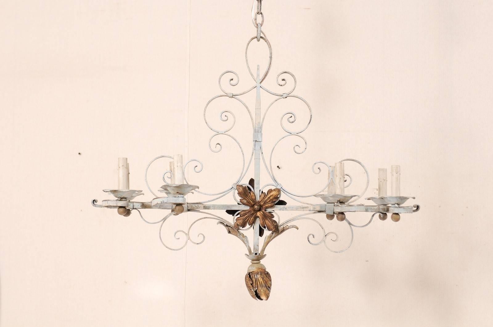 A vintage French eight-light painted iron chandelier. This French Mid-Century chandelier is made up of a series of intricate scrolls, which mingle and intertwine throughout the body. There are large accent flowers at the cross section of the