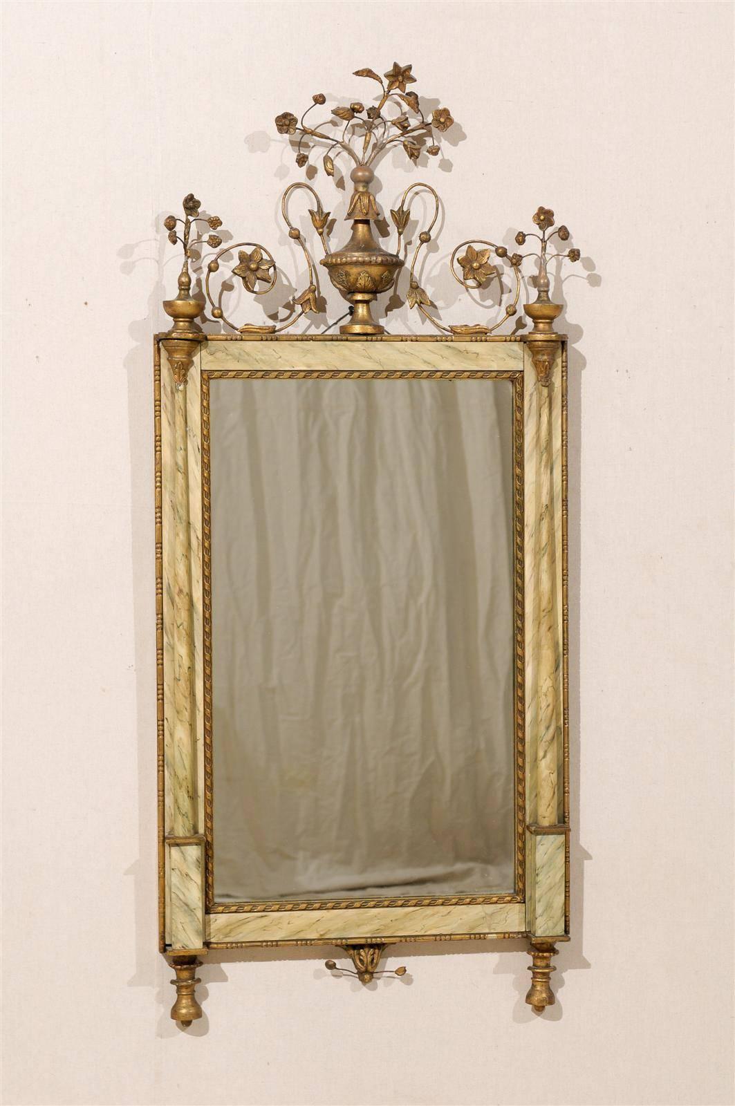 An exquisite mid-20th century, Italian rectangular wall mirror with faux marble frame. This mirror is flanked with two slender columns in the surround. This Italian mirror also has delicately carved and gilded rinceaux accents. This piece would look