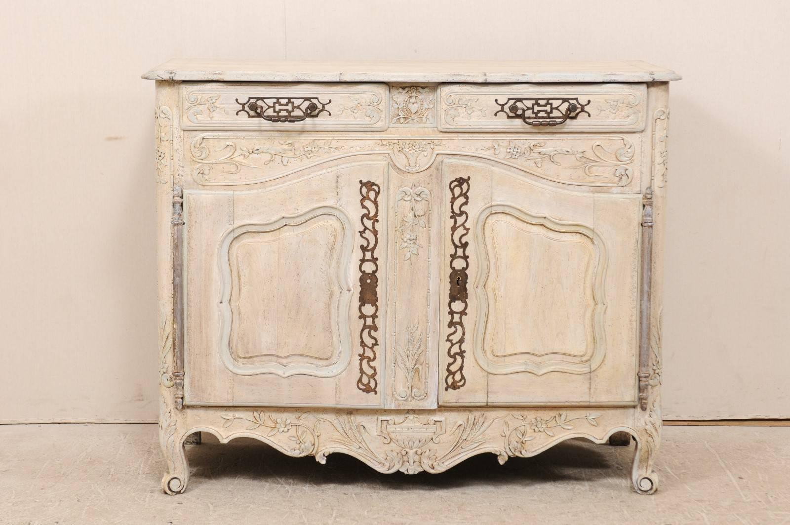 A French, 19th century carved and painted wood buffet. This French wood buffet features two drawers over two doors. The side posts, drawers, doors and skirt have all been delicately carved in a floral and leaf motif. The skirt is heavily scalloped