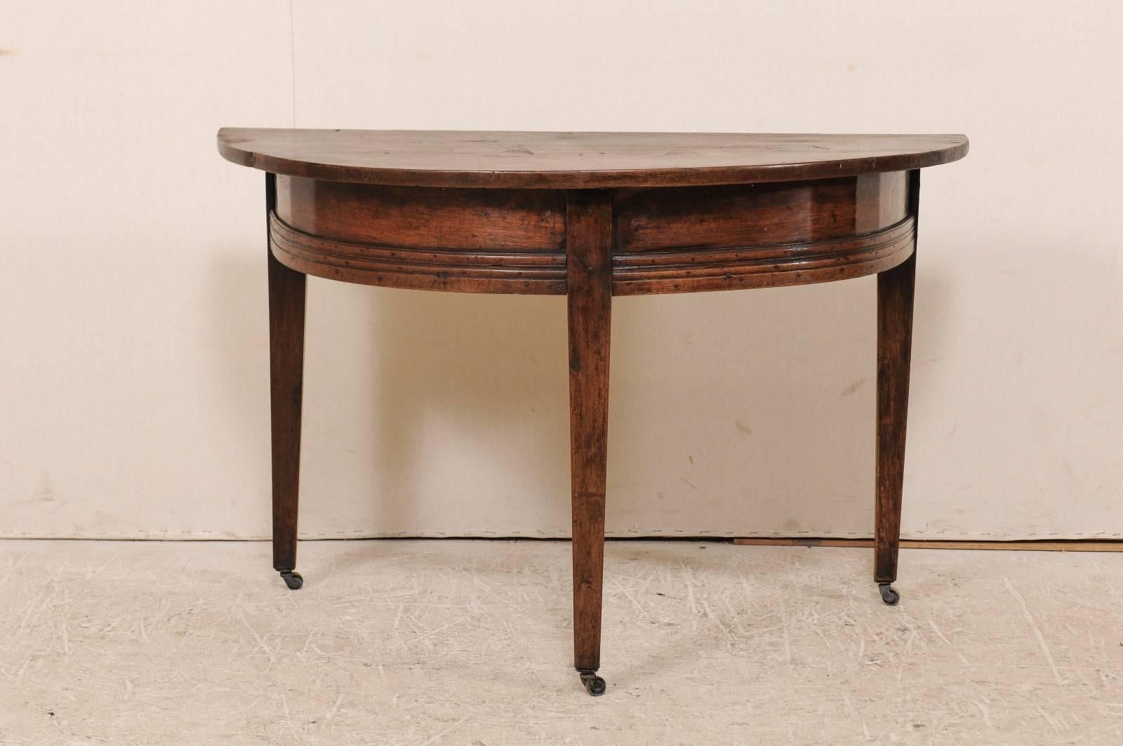 A late 18th century Italian demilune console table. This Italian console table from the late 18th century features nice clean lines, a simple rounded apron with stacked trim detailing across the bottom. The table is raised on three squared and