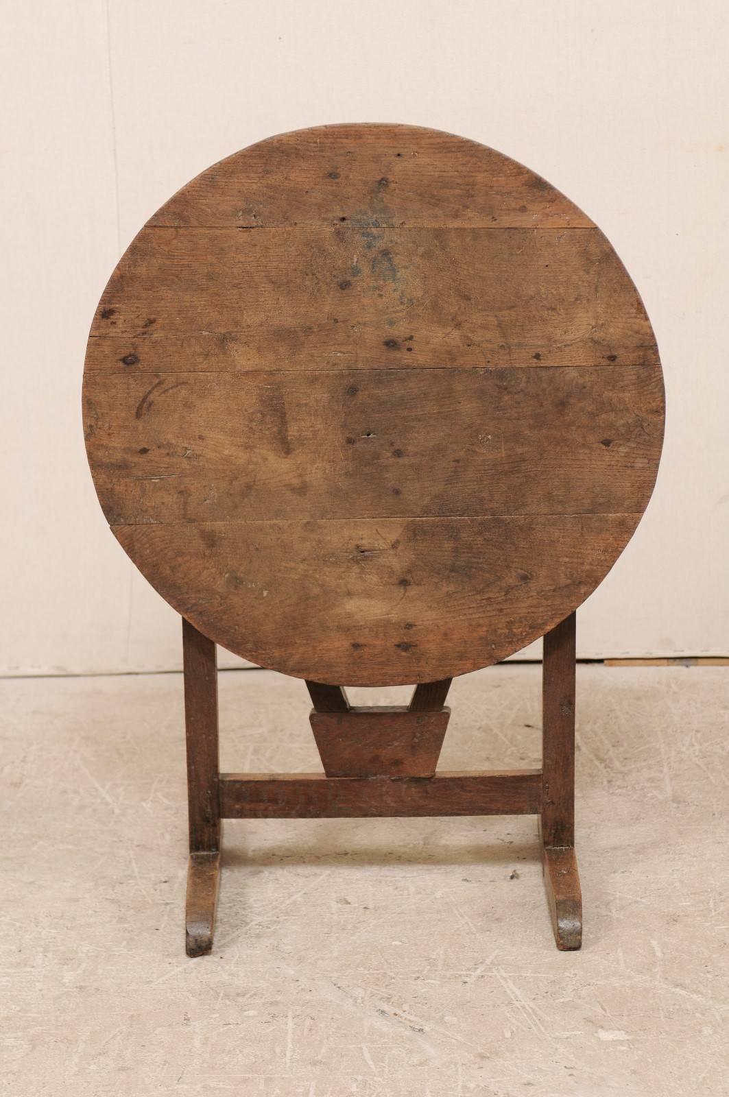 A French 20th century wine tasting table. This round shaped French wine tasting table features the typical tilt top, and butterfly wedge turn which supports the top. This table has some nice wear and patina throughout, reflective of age and use.