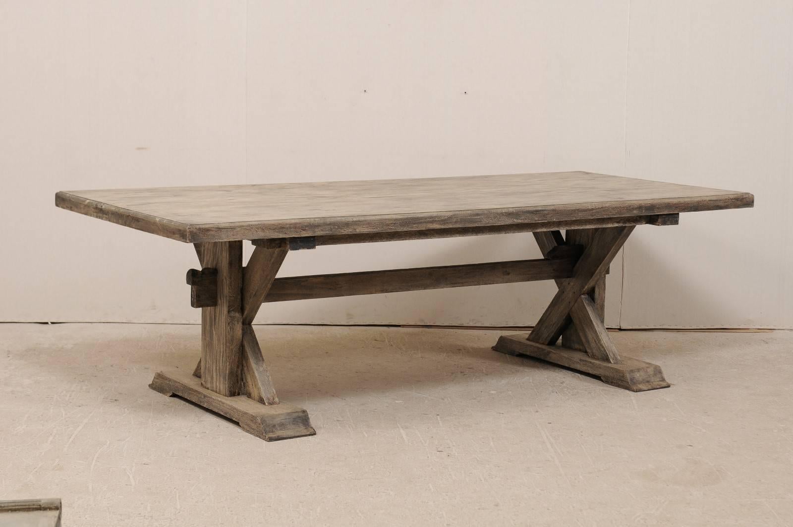 An American trestle base dining room table. This 8.5 foot long, vintage American trestle table with X-frame is made of reclaimed teak wood, which is a very sturdy exotic hardwood. The wood has been bleached and there is a rich charcoal wash, with