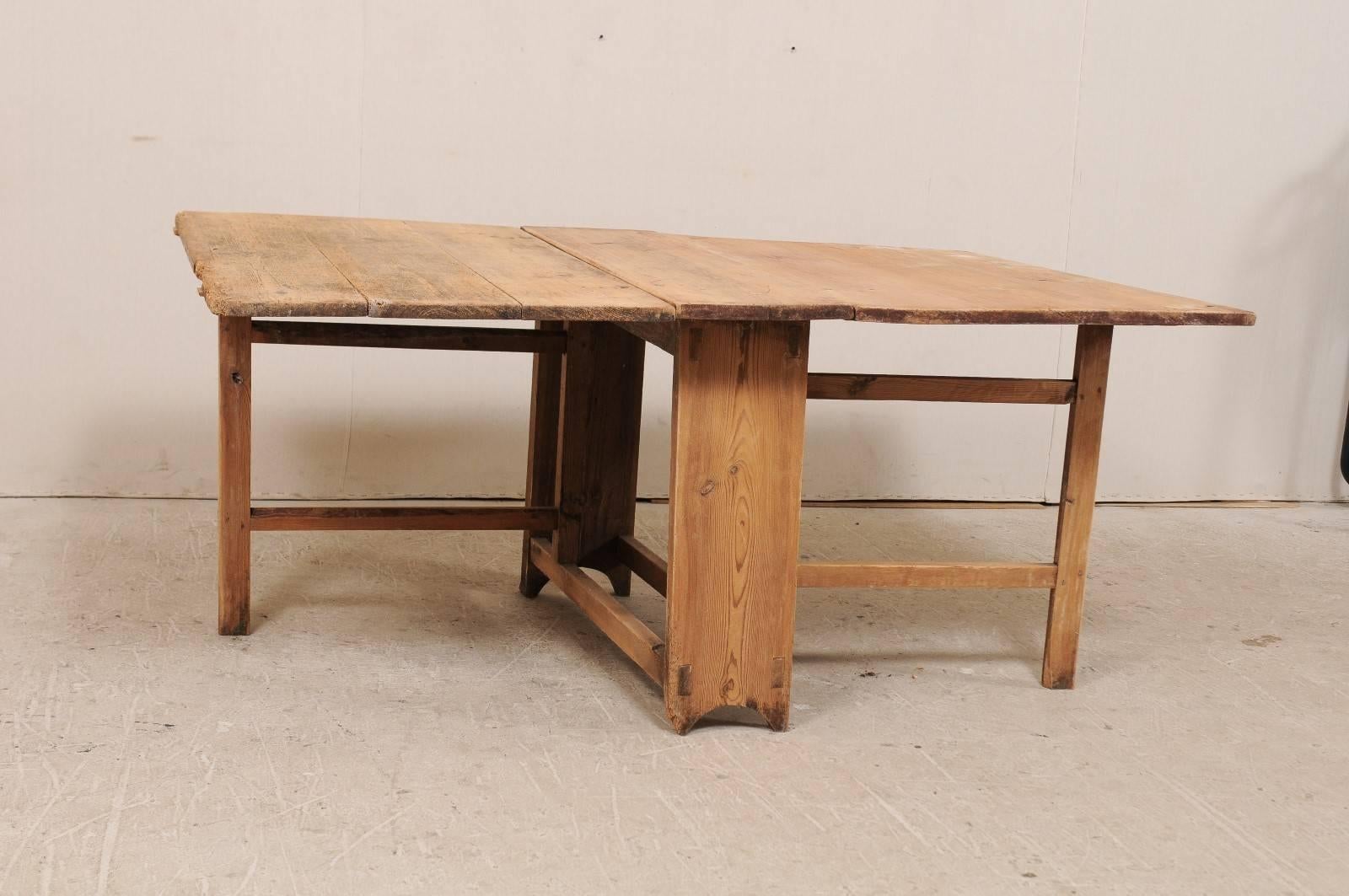Table suédoise du début du 19e siècle en bois, à abattant et pieds de porte. Cette table suédoise antique est dotée de deux côtés à abattant qui prolongent la table jusqu'à 66,5
