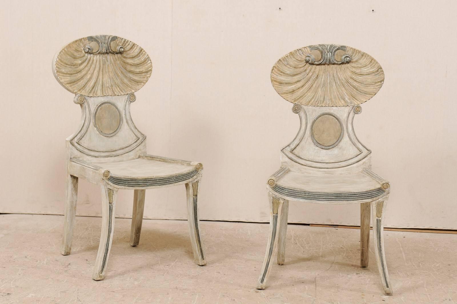A pair of vintage American carved and painted wood grotto chairs. This pair of grotto side chairs feature a shell motif carved at their upper backs, typical for this Italian style chair. The chair backs are quite curvy and fluid with scroll work at