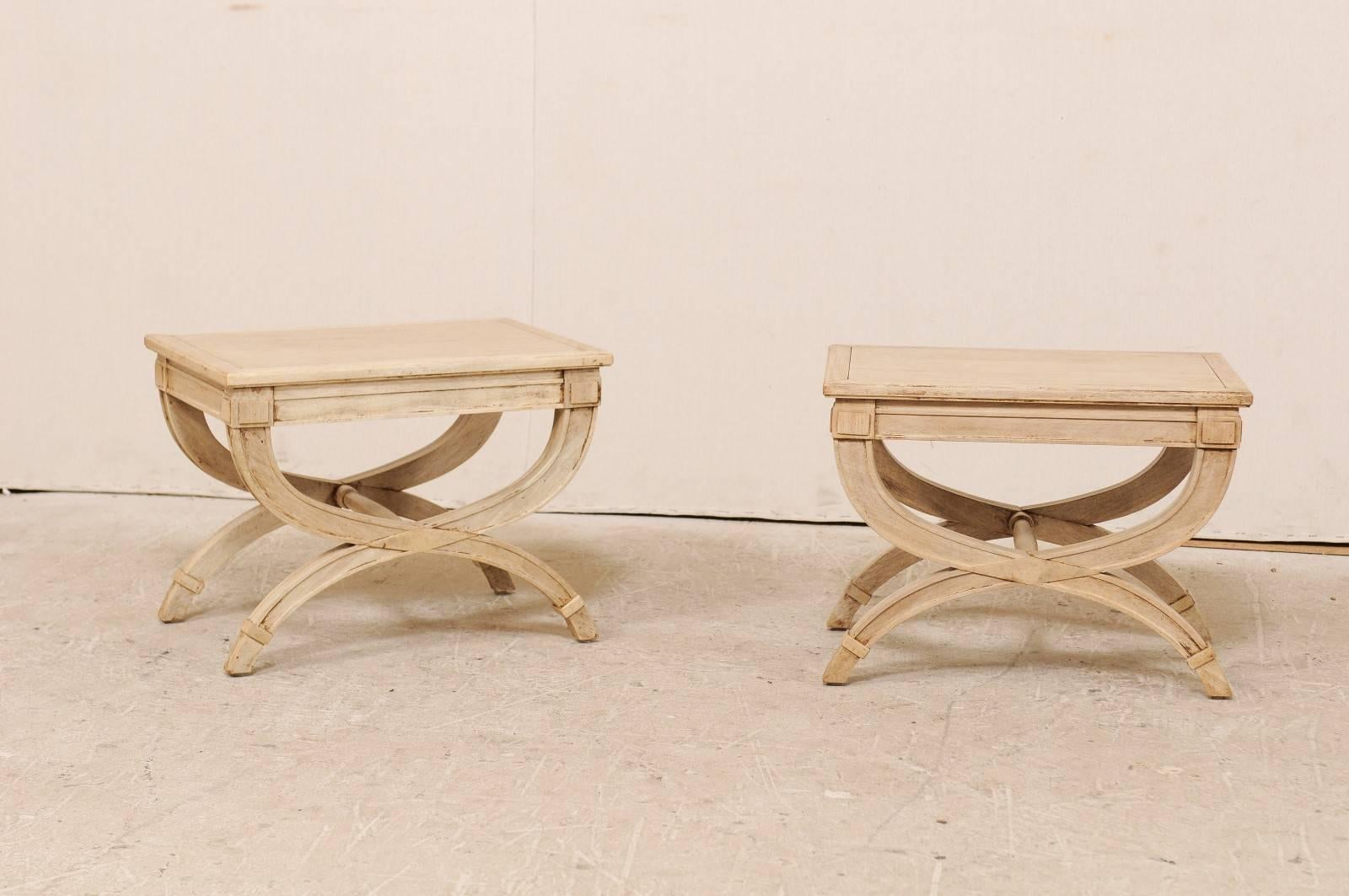 A pair of American Dante style wooden stools. This pair of vintage American natural wood stools features a rectangular seat and Dante style legs (double half-moon legs that are connected by a turned cross stretcher). This pair of vintage Dante