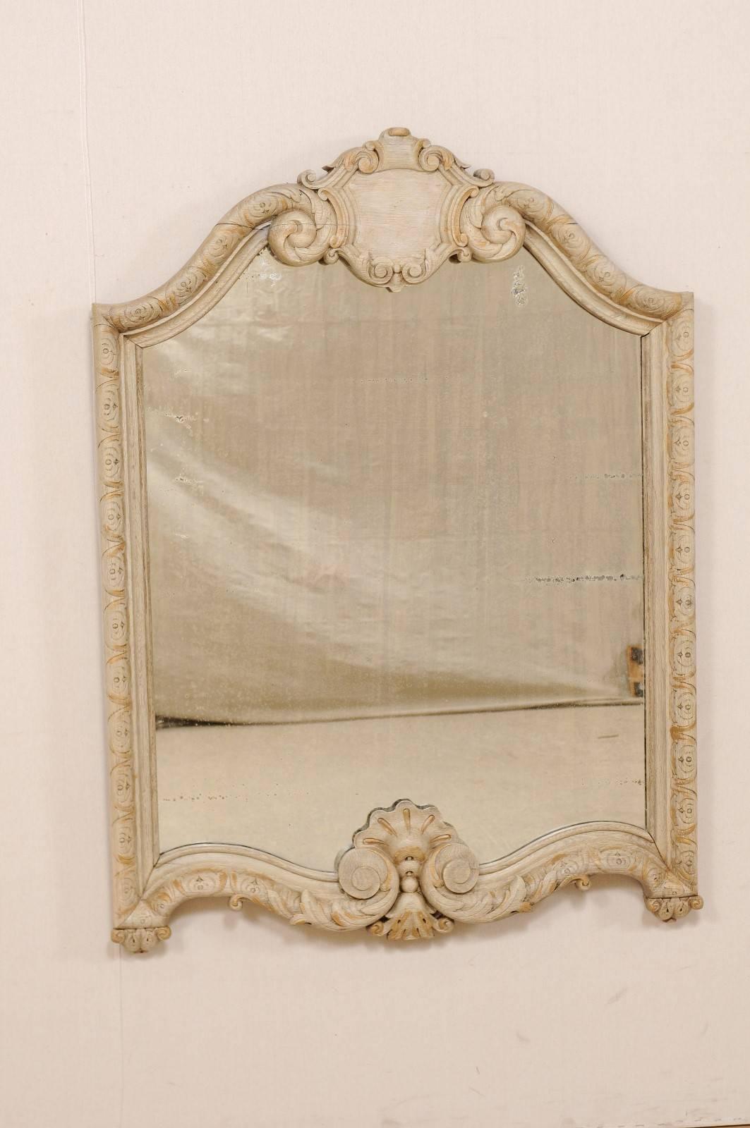 A mid-19th century Italian carved wood mirror. This Italian mirror from the mid-1800s features a carved wood surround with arched crest with central cartouche, scrolling accents wrapped in acanthus leaves, and egg and dart patterning around all