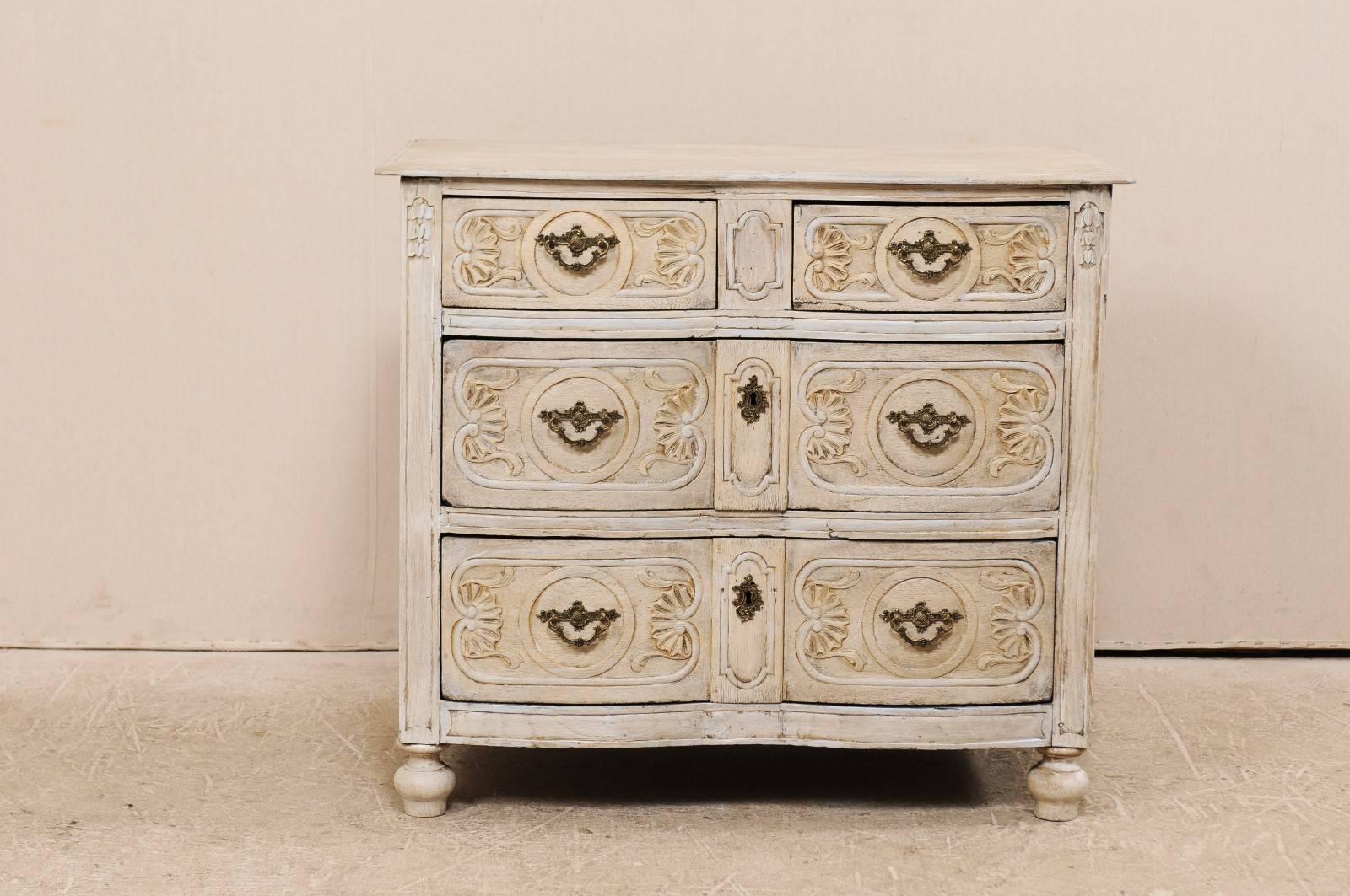 A French early 19th century scalloped front chest. This French chest from the 1820s has two small drawers over two larger drawers. Each drawer is elaborately carved with curved acanthus leaf, shell and framed carvings about the Rococo style