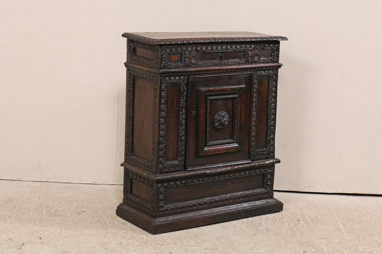 An Italian early 18th century small sized cabinet. This exquisite Italian cabinet, trimmed in richly carved moldings throughout, features a lift top and single door centered at it's lower base which opens to an inner shelf. This wood carved cabinet