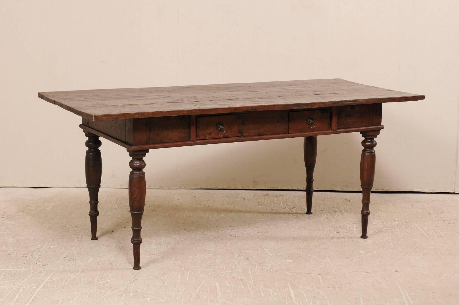 A Brazilian table from the early 20th century. This antique Brazilian table features two small drawers on one side and beautifully turned legs. Each drawer is decorated with simple ring pulls. The wood is a nice rich brown. This table has a deep