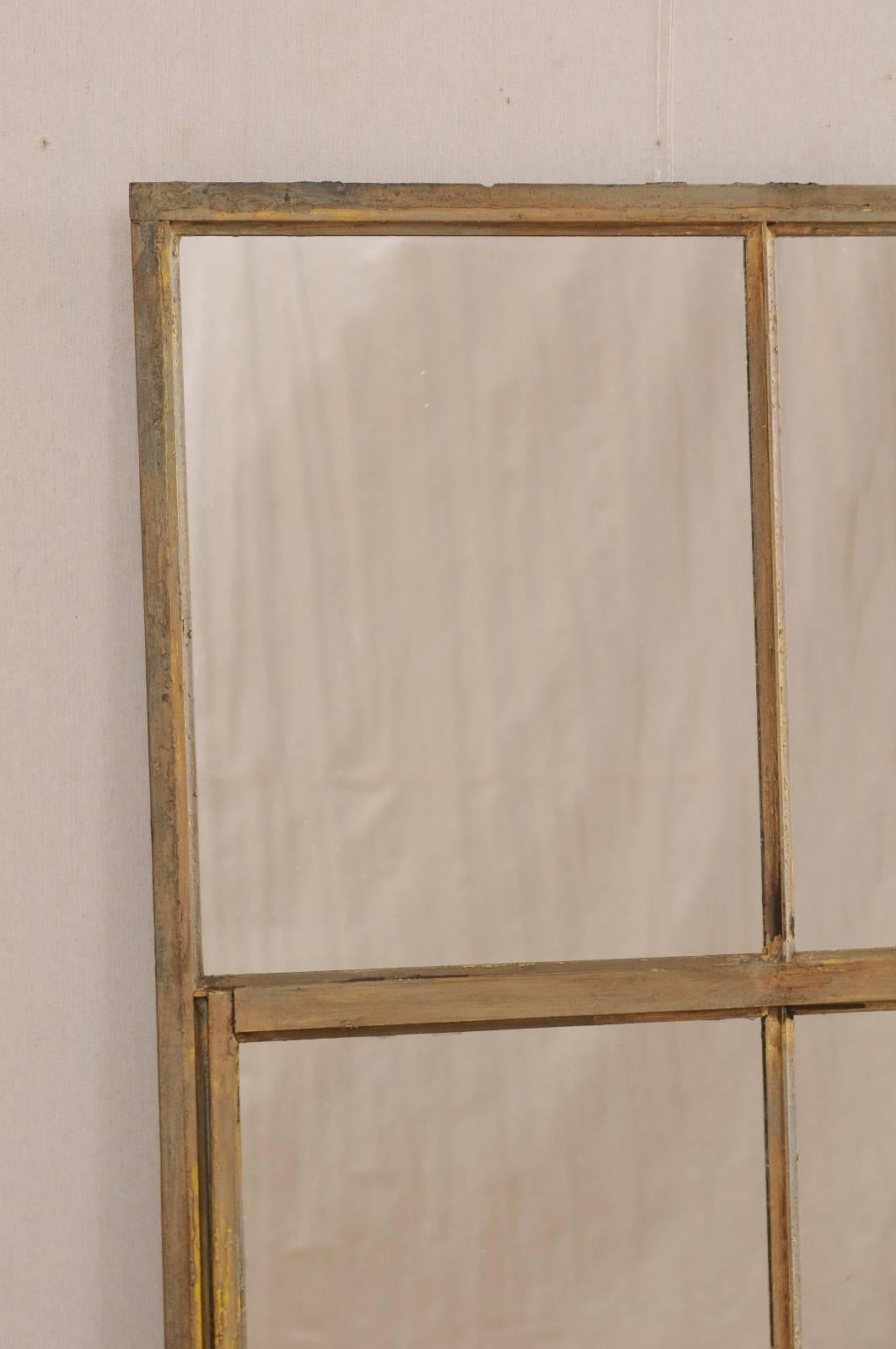 A French early 20th century paneled metal mirror. This antique French mirror features a large sized painted iron frame of nine panels. The iron frame retains it's original paint finish, primarily in a gold hue with nice patina. This French