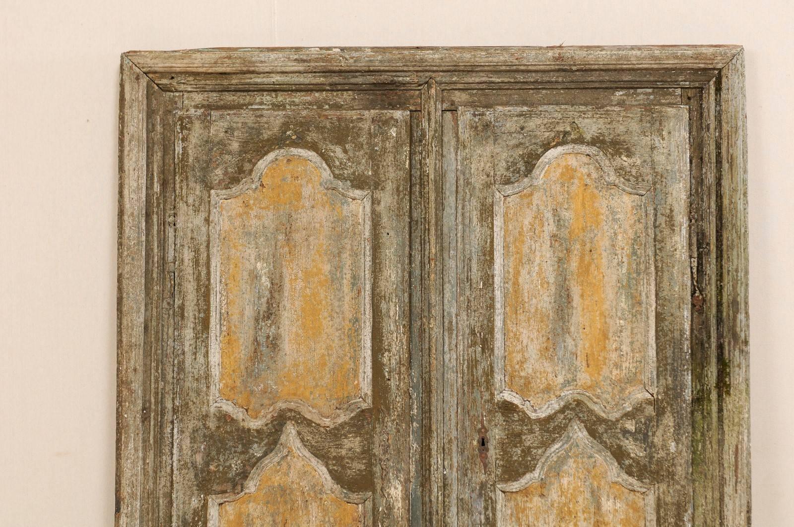 A pair of 18th century Italian doors within their original casing. This pair of Italian doors and casing from the 18th century feature door fronts beautifully decorated with carved and painted recessed panels. The panels have curvaceous tops and