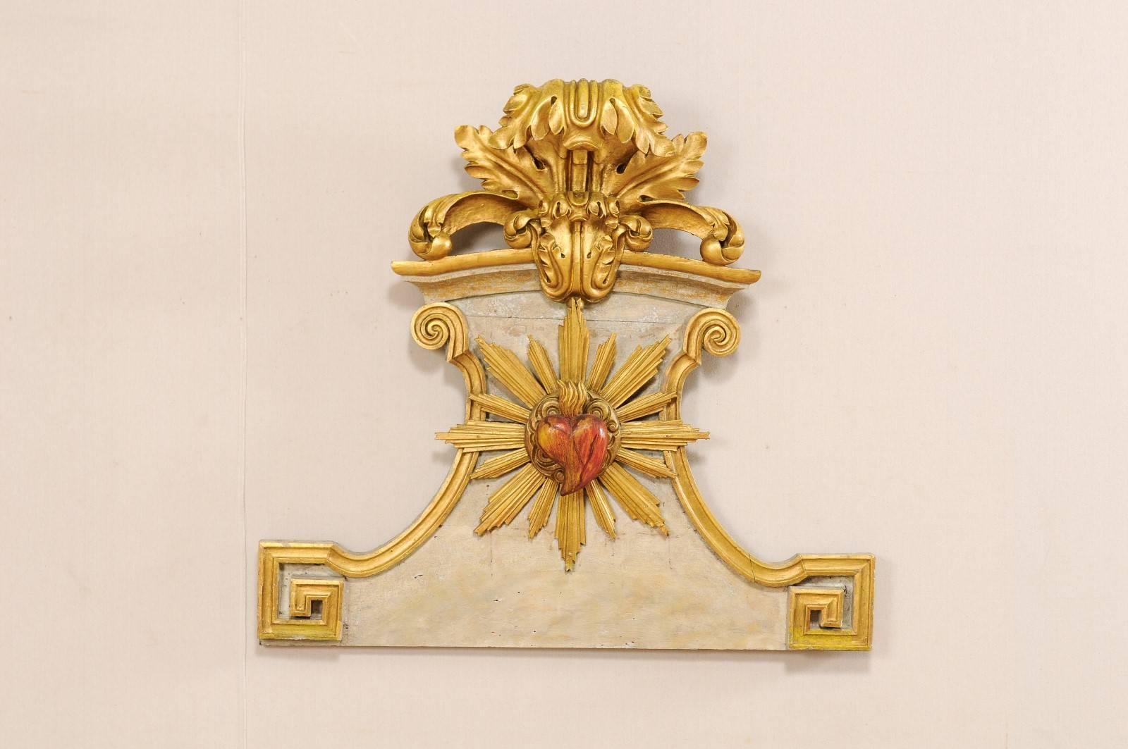 An 18th century Spanish carved wooden wall plaque. This Spanish wall decoration features beautiful gilded three dimensional carvings depicting a scrolling acanthus leaf motif at it's crest, and a flamed heart bursting from rays at the plaque's