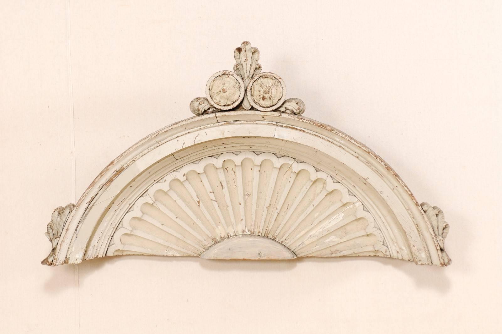 A French 19th century carved wood wall decoration. This antique French architectural wall ornament features an overall half-moon shape adorn with a pair of encircled flowers and leaf motif rising from the top centre crest. The rounded edges are made