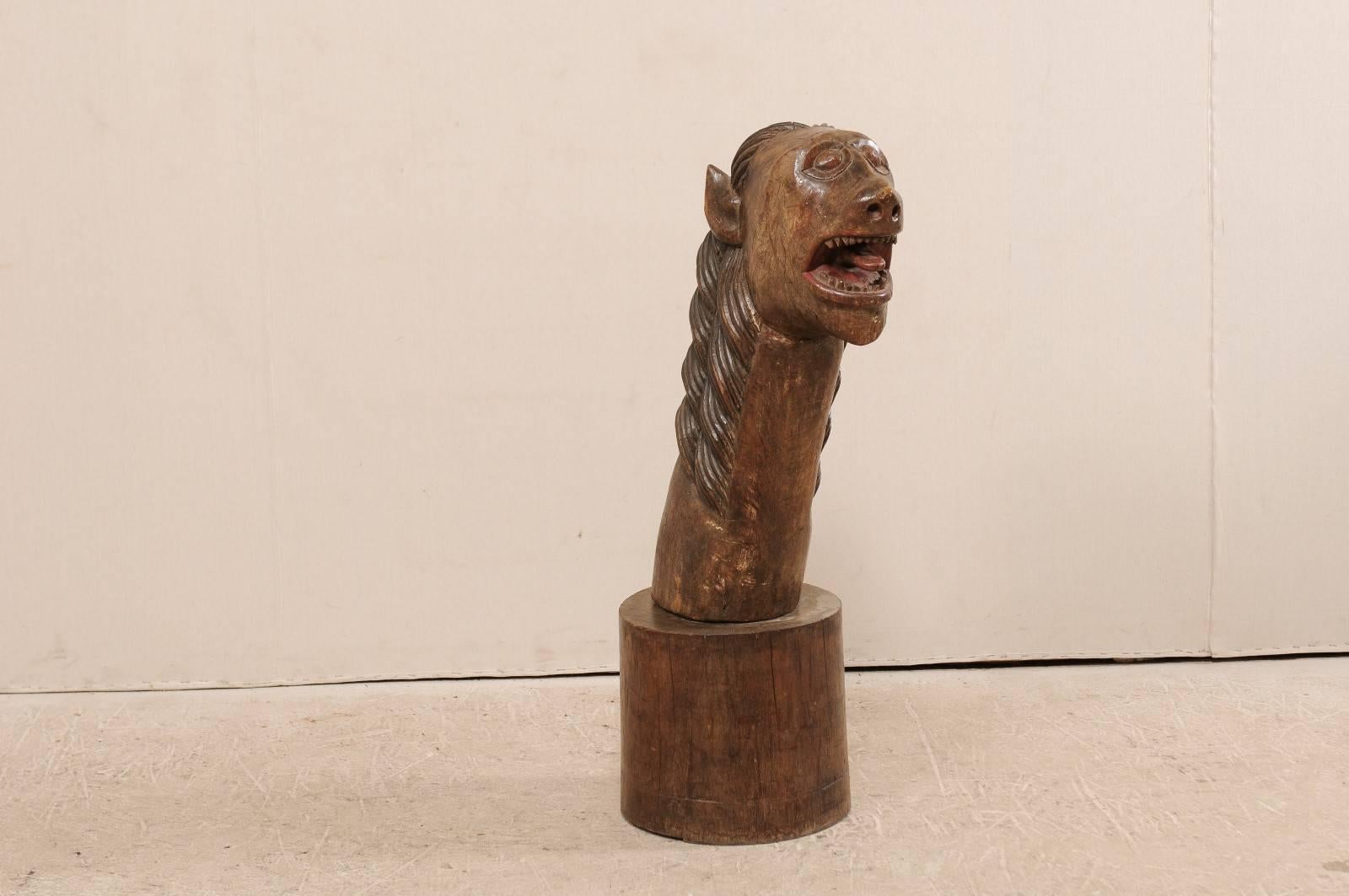 A 19th century Brazilian Folk Art wood sculpture. This antique Brazilian Folk Art piece features a hand-carved figure of a wide-eyed, open mouthed animal with long neck and mane. The animal is displaying a wickedly playful projection of its tongue,