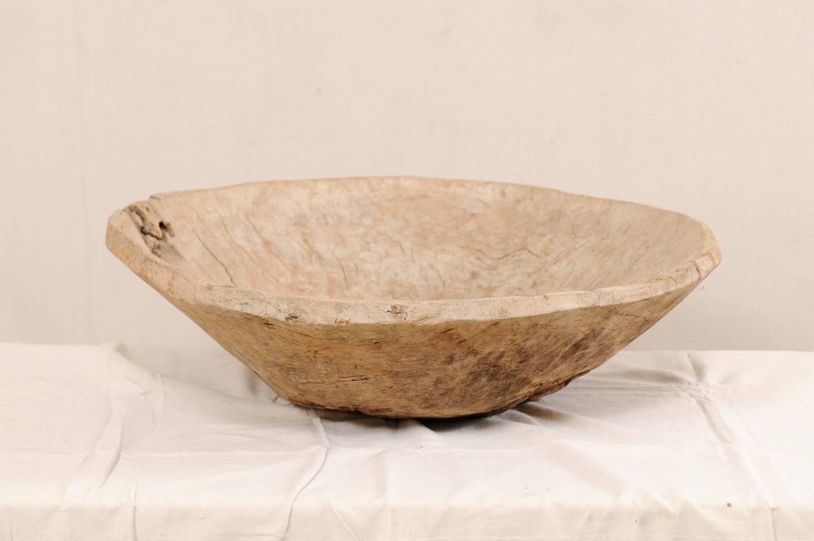 An antique European wood bowl. This beautiful wood bowl has been hand-carved from a single piece of burl wood. It is round in shape, with widest part being at the top lip and sloping down and inward towards the centre. The natural burl wood shows