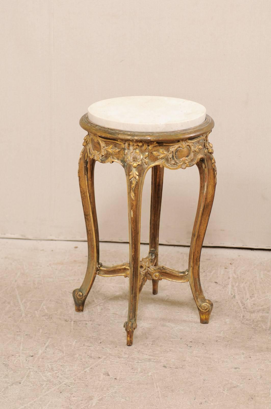 A pair of French midcentury round marble top occasional tables. These French tables from the mid-20th century each feature a round honed marble top, and beautifully carved wood base with gilt details throughout. The circular-shaped skirt is adorned