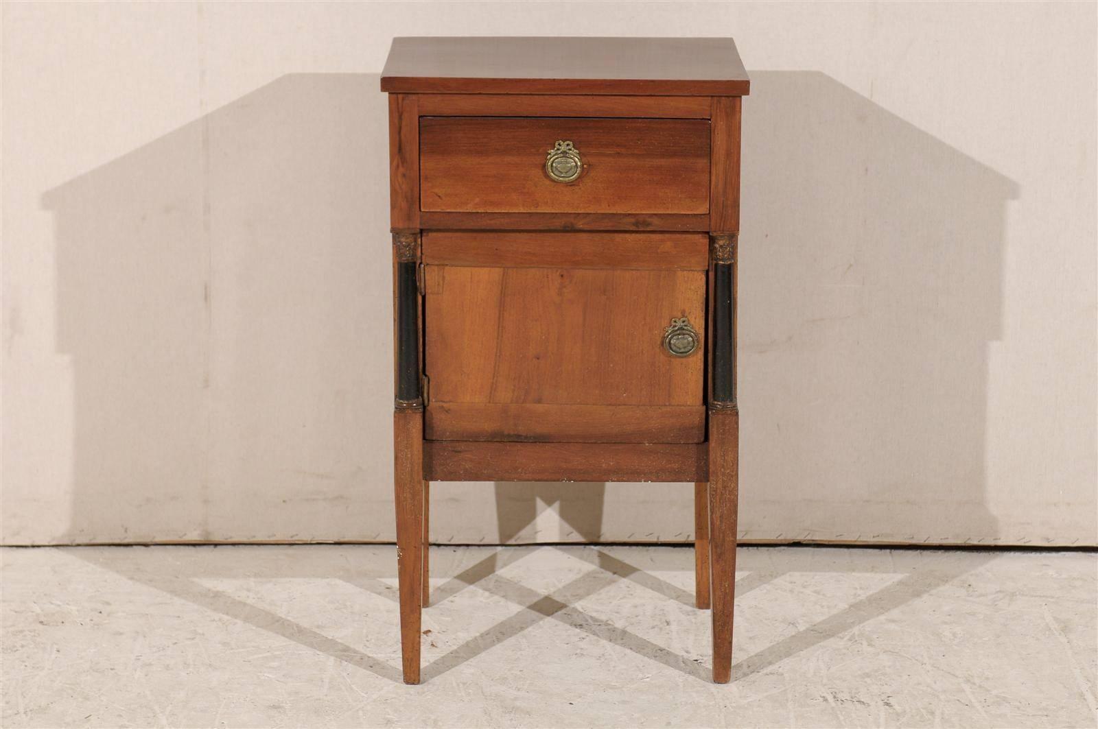 A French early 19th century Empire single drawer, single door wood chest. This lovely little chest is flanked with black half-columns and stands on tapered legs. The back of this piece unfinished, typical of the time period.