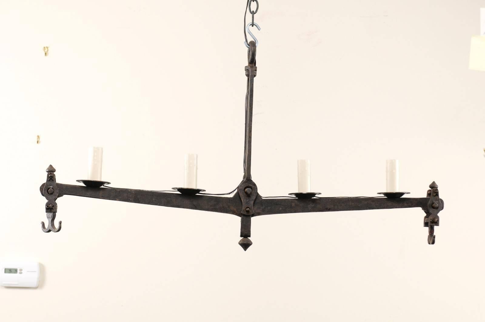 A midcentury French iron scale chandelier. This French chandelier features a central beam from a mid-20th century wrought iron scale. This four-light chandelier has a simplistic and appealing design aesthetic. There is lovely, aged patina