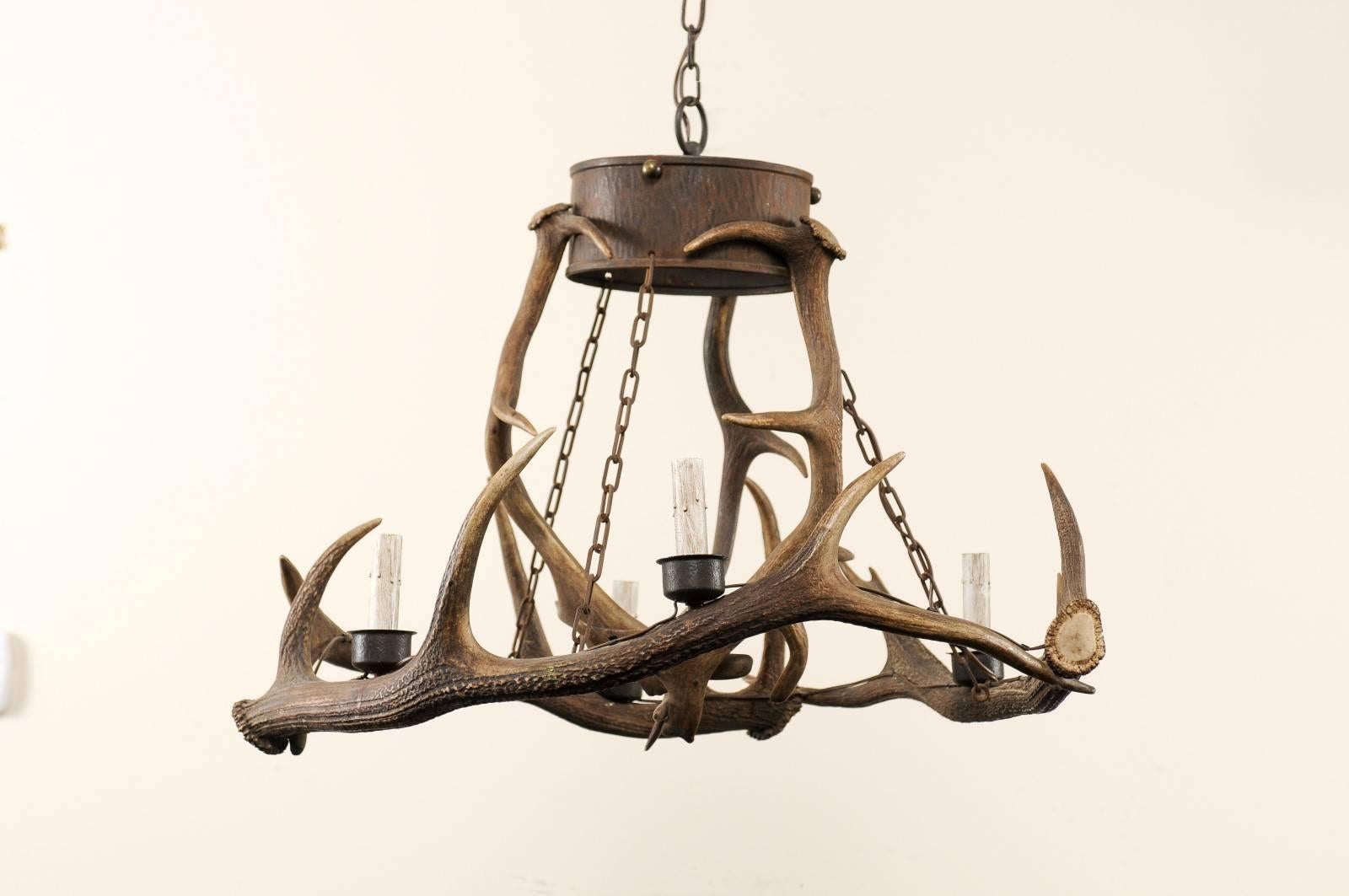 A French deer antlers chandelier. This four-light French vintage chandelier features interlocked deer antlers, which make up a round-shaped body and are connected to an upper metal ring with links, circa 1950. This French midcentury antler