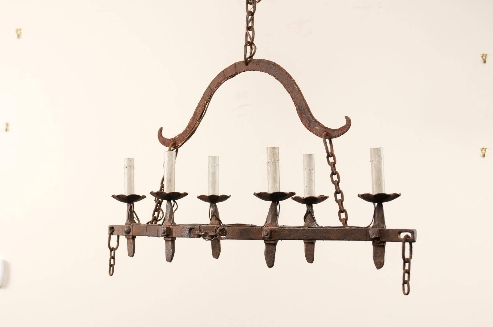 A vintage French six-light iron chandelier. This French midcentury chandelier features a centre piece that could best be described as boat shaped, with two cross bars at it's centre. There are six arms mounted around it's perimeter, which are topped