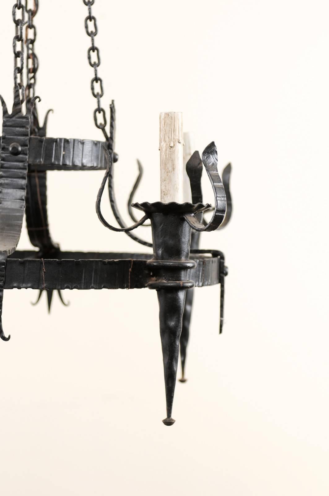 Martelé Lustre français vintage à quatre lumières en fer noir avec accoudoirs en forme de torche en vente