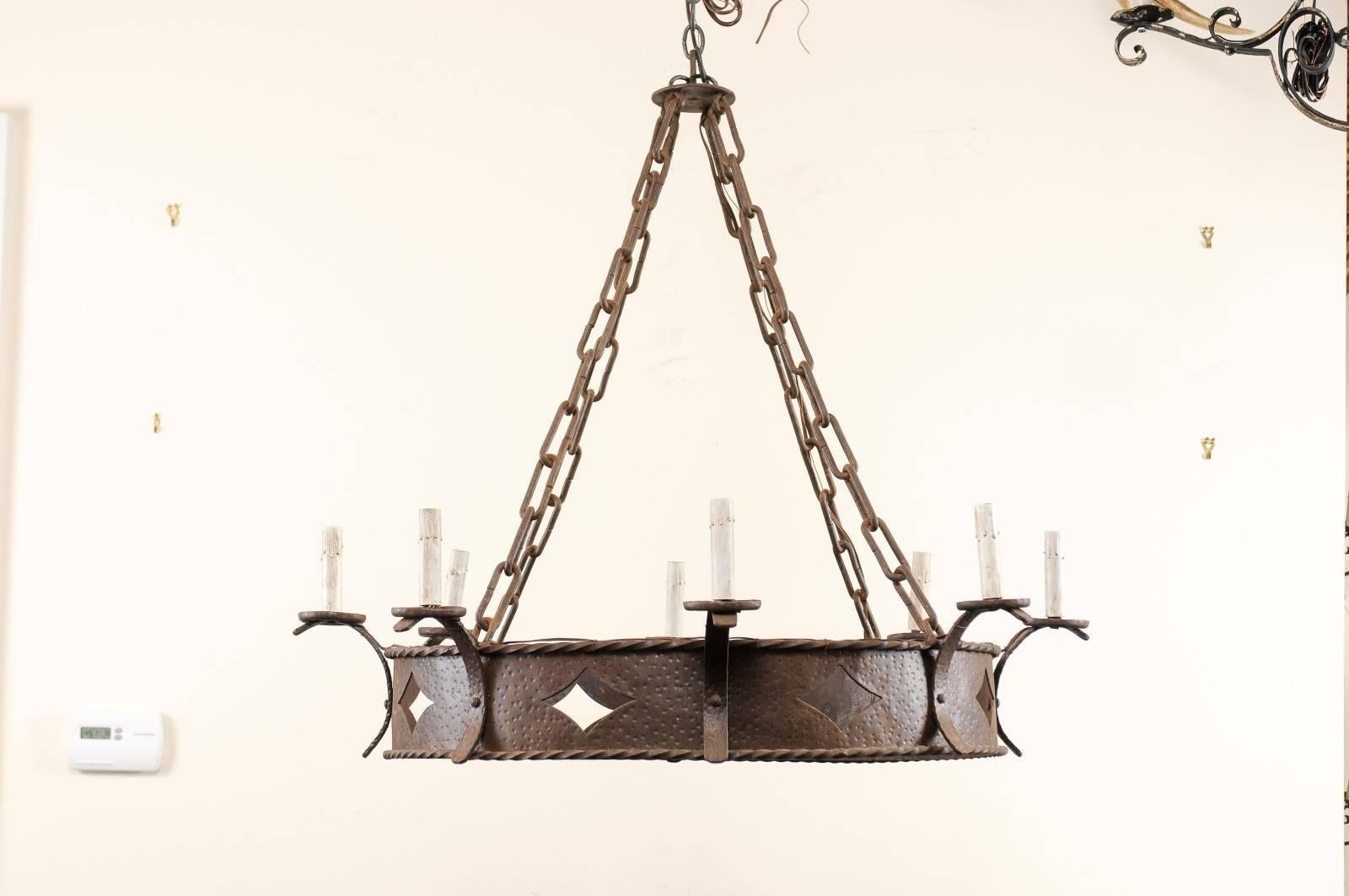 A midcentury French ring-shaped wrought iron eight-light chandelier. This French chandelier features a large center ring which is adorned with a pierced cut diamond pattern and twisted iron details about the upper and lower edges. There are eight