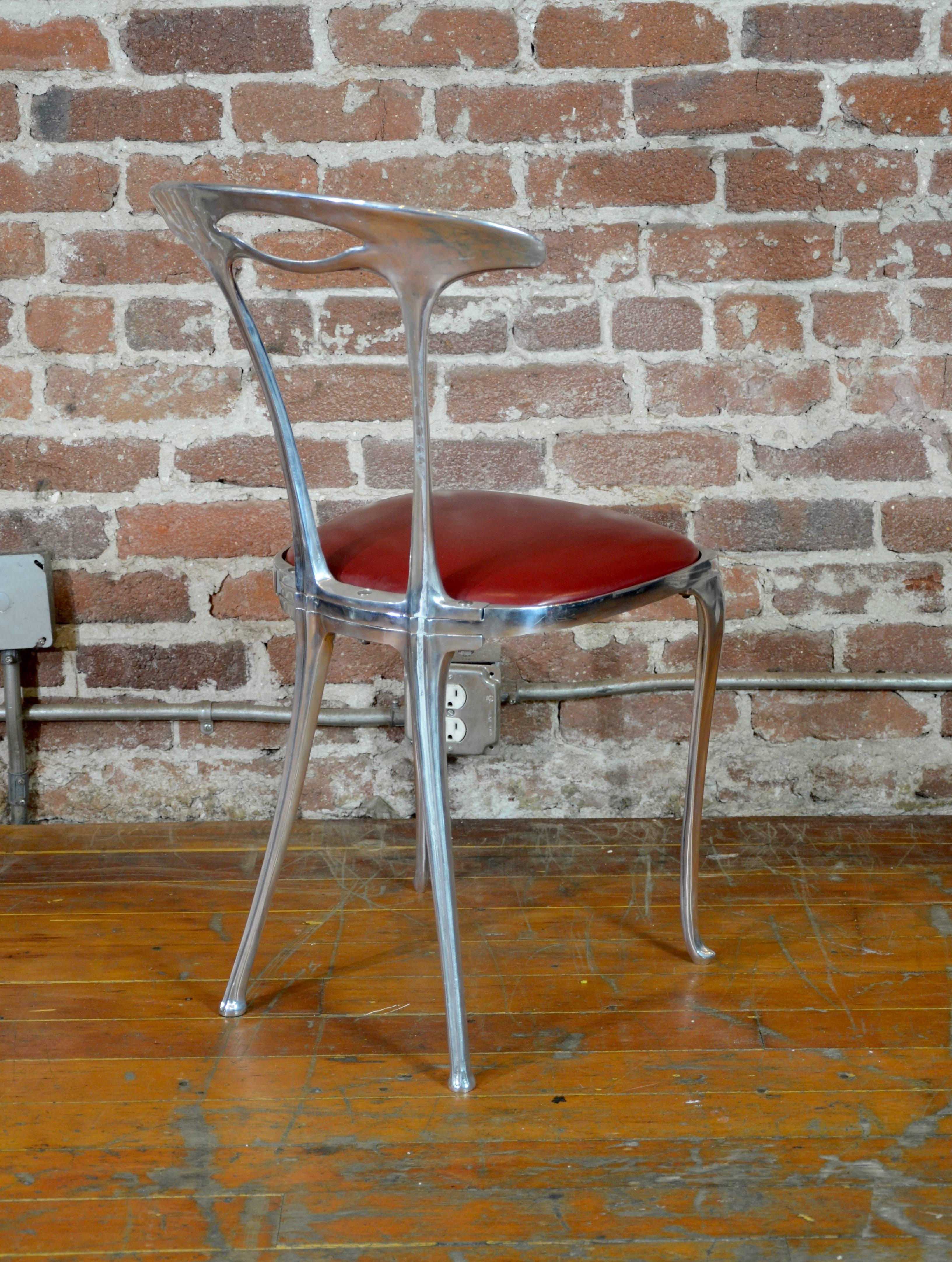 Nice set of 10 cast aluminum dining chairs by Thinline. Simple and elegant form. Red leather upholstered seats.