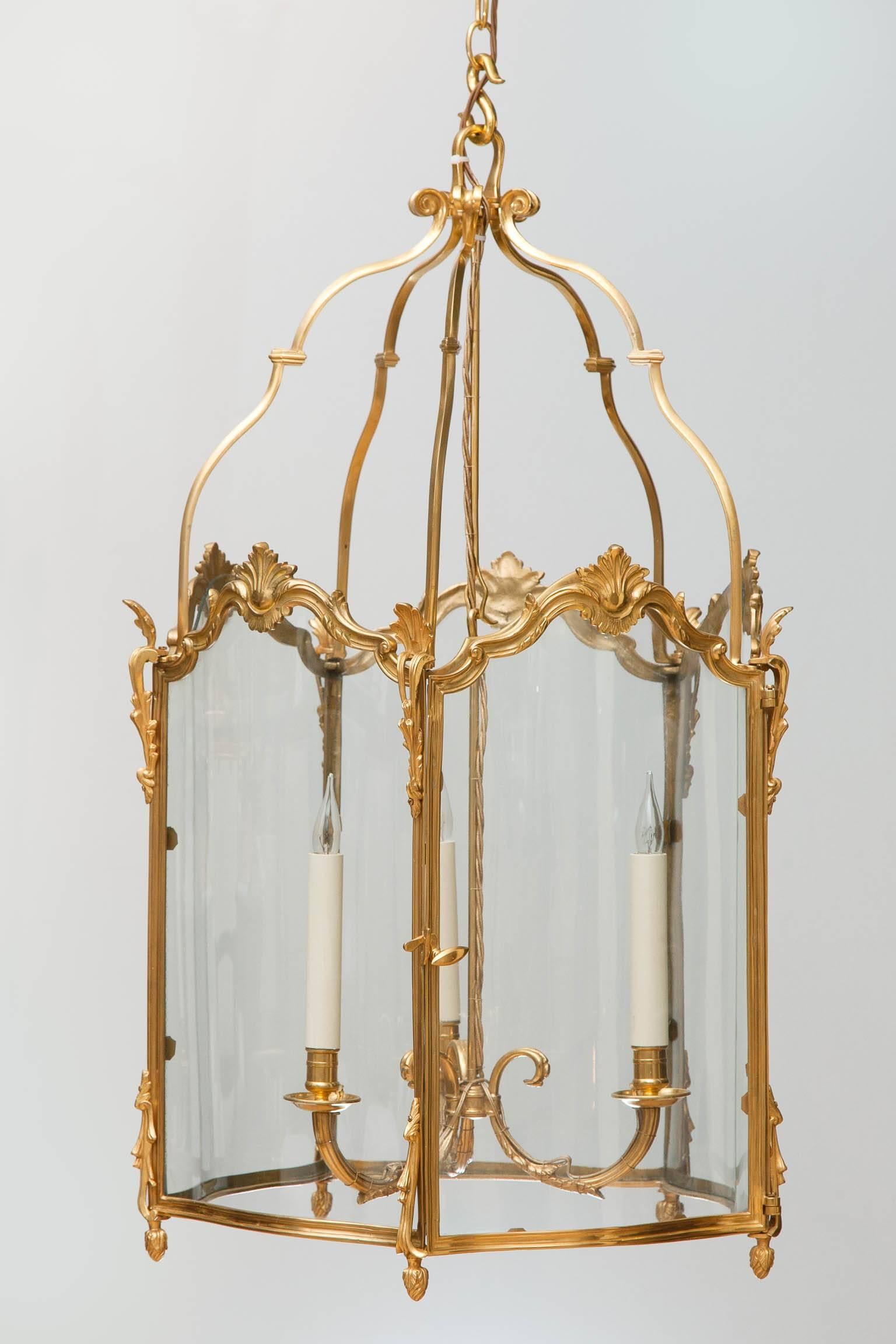 Pentagonal lanterns with five curved glass panels including the door with cast incised metalwork, suspended from five shaped brackets with small cast finial feet in the shade of buds with leaves. Original three arm pendants with acanthus decoration.