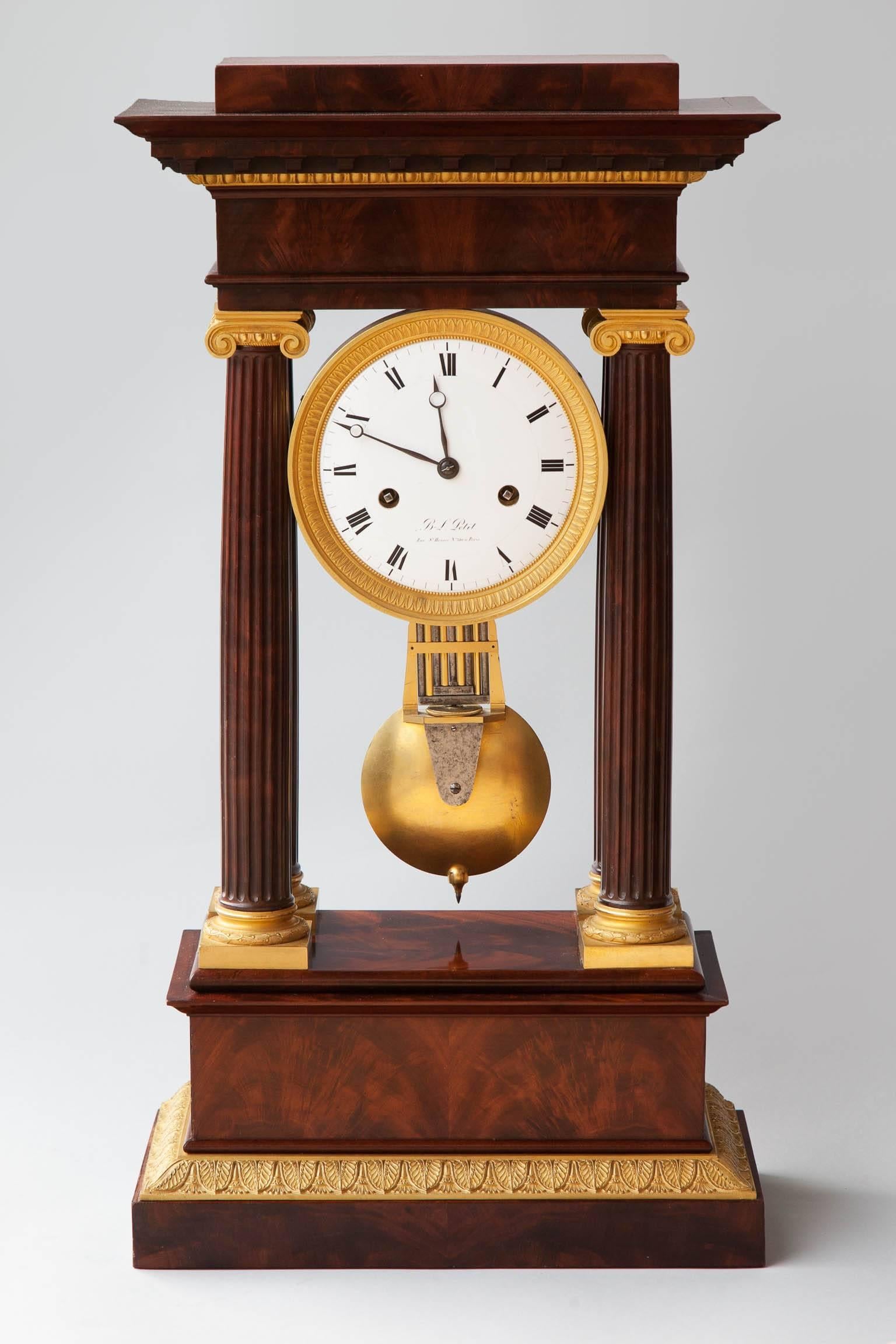 Two train movement count wheel striking on a bell, with chiming on the hour and half-hour. Flame mahogany veneered case with supported by four mahogany Ionic columns and mounted with finely incised gilt bronze mounts. 
The enamel clock face in
