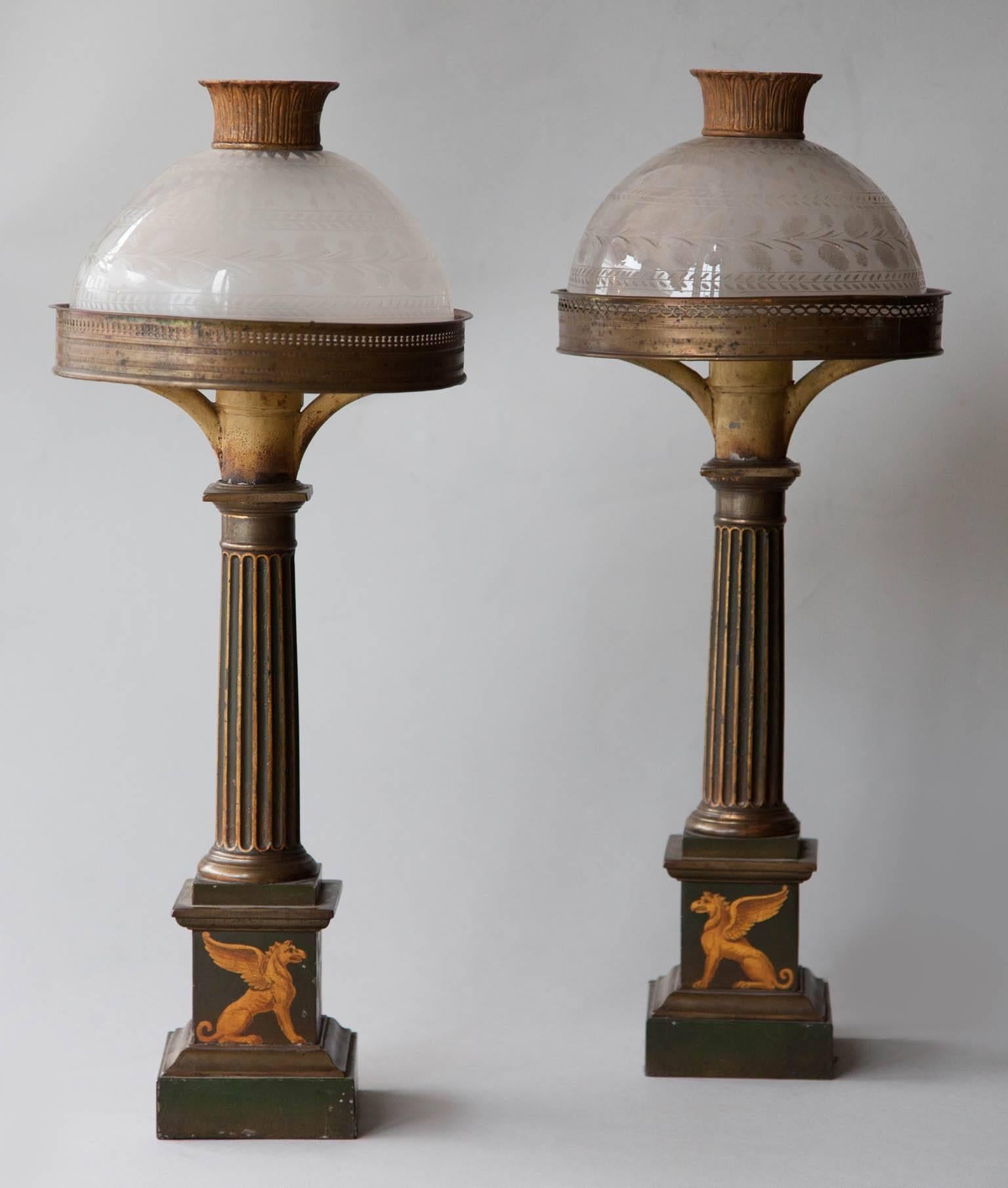 Early 19th century French Carcel table lamps with sin umbra shades, fluted columns on rectangular plinth bases. Decorated in gold with painted Griffins and Poppies.
Acid etched glass shades, one is a replacement.
Currently electrified for the
