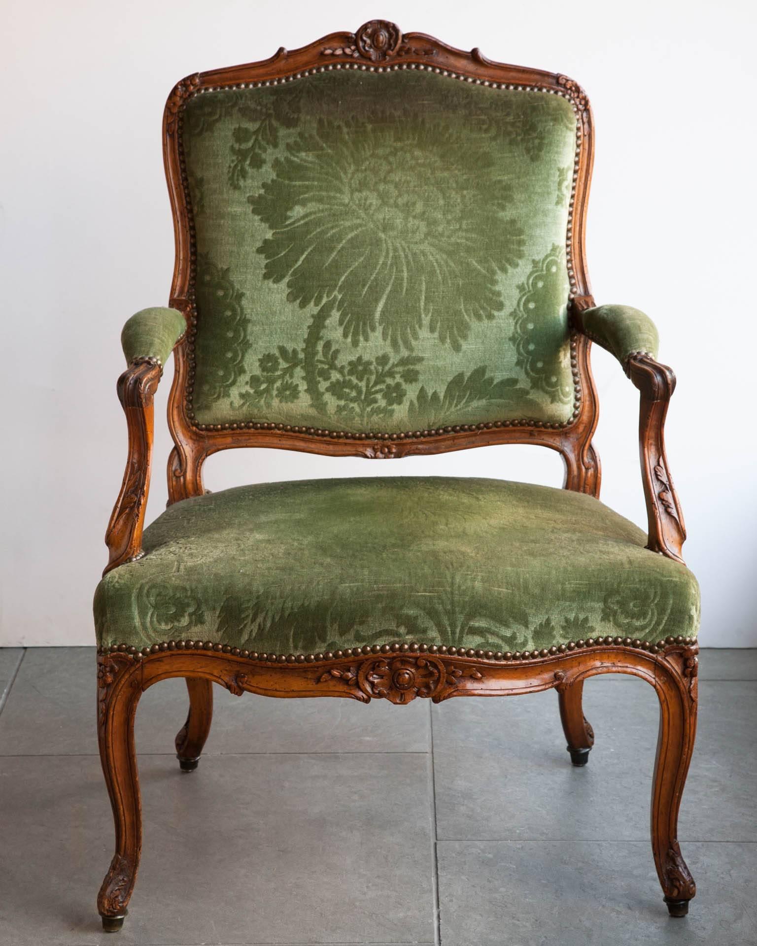 Mid-18th century walnut open armchair. With carved flowers and acanthus leaves. Cabriole legs terminating in scrolls with tipped metal feet. Upholstered in cut green velvet,
Loire Valley, France. Circa 1760